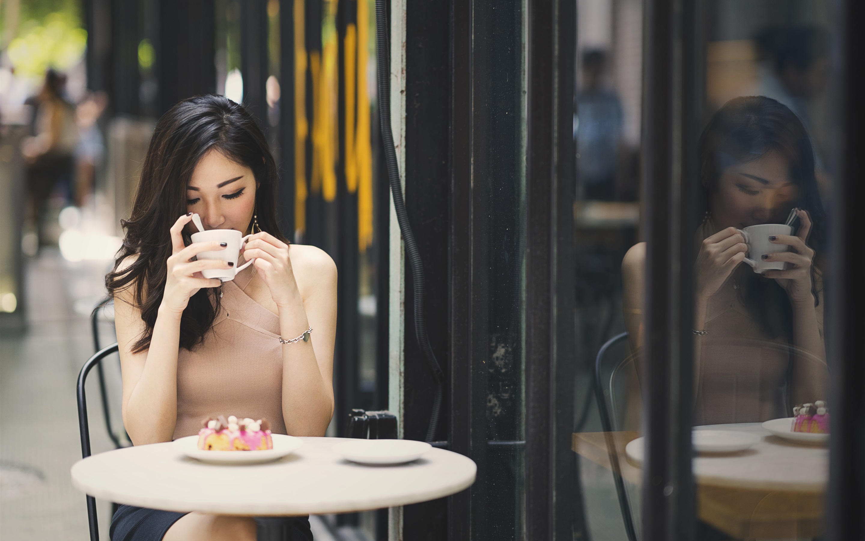 Азиатская девушка с чашкой кофе за столиком на улице