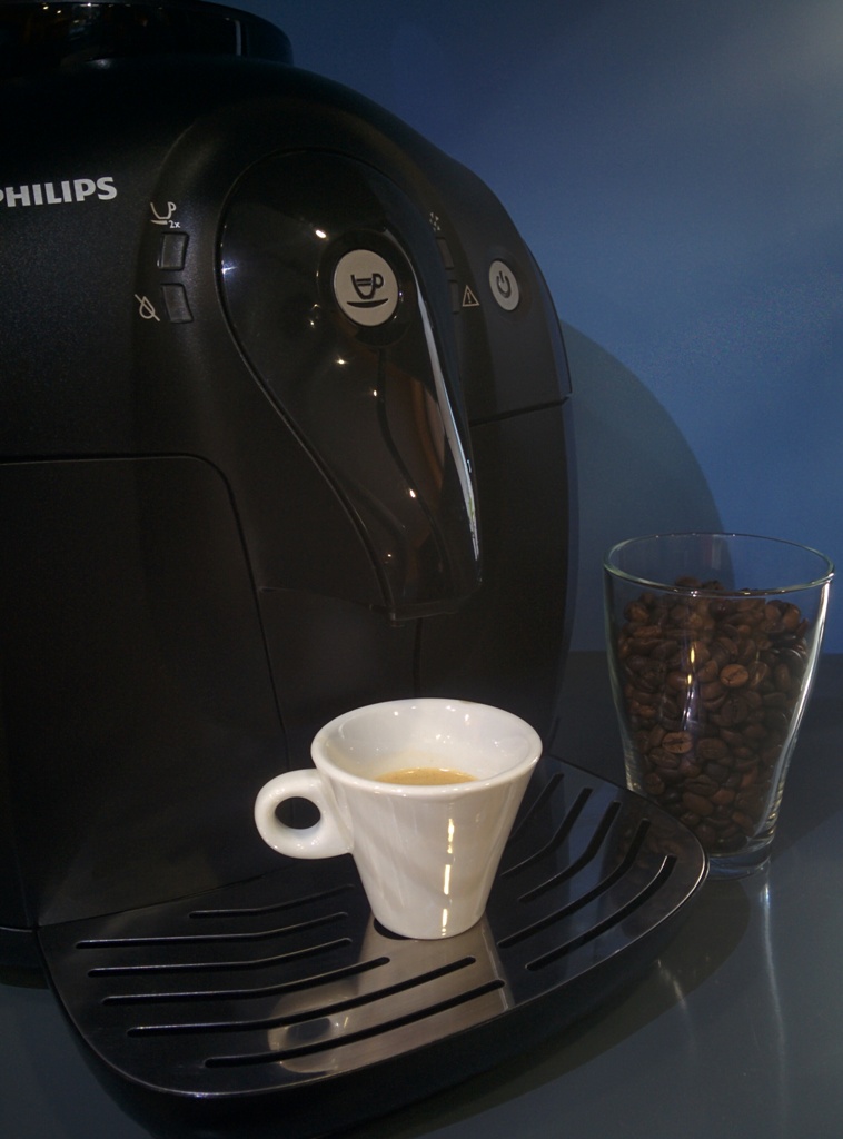 Автоматическая кофеварка для дома с чашкой кофе и стаканом молотых зерен