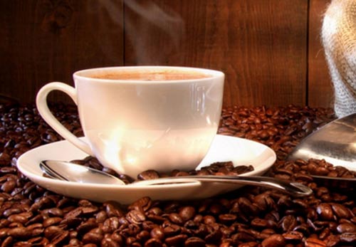 Чашка кофе на обжаренных кофейных зернах. Покупай кофе у нас по доступной цене.